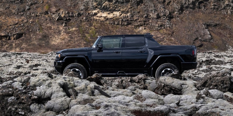 Hummer EV Pickup parked by large rocks